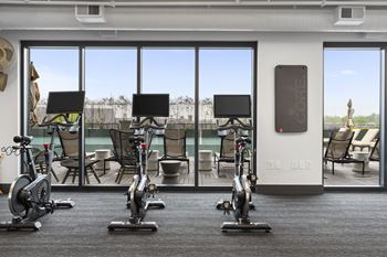 A gym with exercise machines and a view of a pool